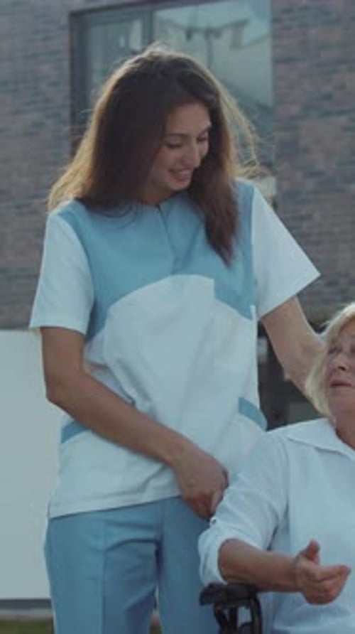 Woman Pushing Senior Woman in Wheelchair Outdoors