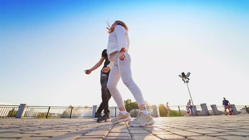 Street dance of young couple. Dancing pair performing freestyle dance in outdoor urban setting.