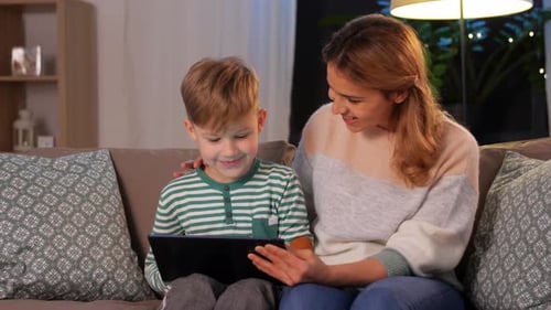 Mother and son using tablet on couch at home