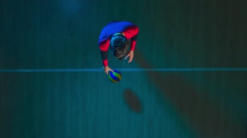Top View of a Young Man Hitting Ball on Wooden Floor Tossing and Hitting the Ball in Jump