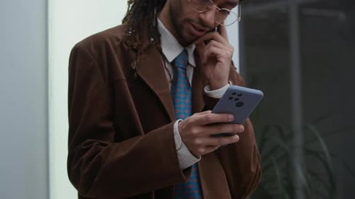 Konzentrierter junger Geschäftsmann aus Biracial nutzt Smartphone im Bürogebäude