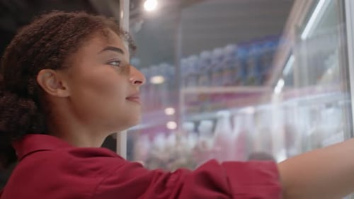 Woman Opening Door of Fridge and Reaching for Bottle of Milk