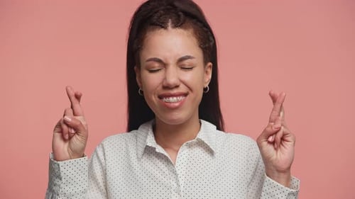 Hopeful Black Woman Crossing Fingers on Pink Background