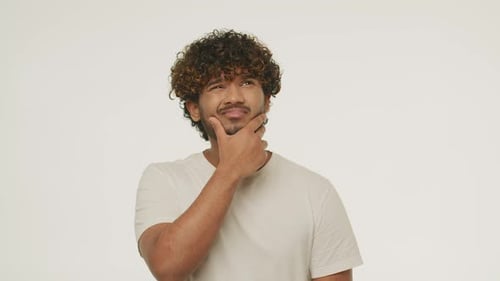 Confused Indian Guy Touching His Beard Studio Footage of Bewildered Young Man Thinking About Problem