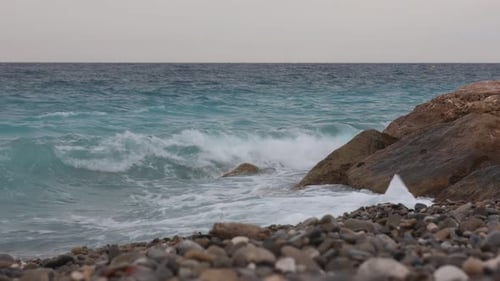 Beautiful view of wavy sea, rocks and pebbles on beach