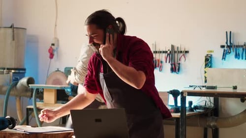Un menuisier dans un atelier d'assemblage ayant une conversation amicale sur téléphone portable avec un client
