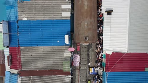 Aerial Top-Down View: Train Arrival at Mae Klong Railway Market, Thailand. Tourists Dangerously Hud