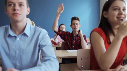 Students at Desks Listen to Teacher Raise Hand