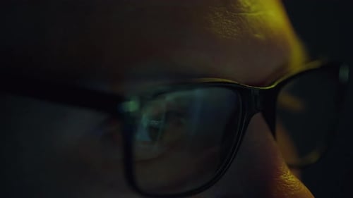 Die Augen eines Geschäftsmannes im Rampenlicht, der nachts arbeitet, intensiv Informationen studiert und