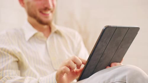 Young Adult Smiling and Using Tablet Device Indoors