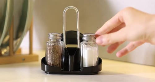 Mujer tomando una coctelera con sal en la mesa cerca de la pared blanca, primer plano