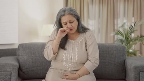 Mature Woman Coughing on Couch Indoors