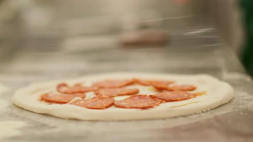 Chef Adding Pepperoni Slices to a Fresh Pizza
