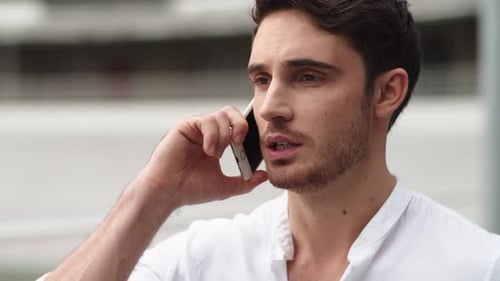 Serious businessman having important mobile phone conversation outside office