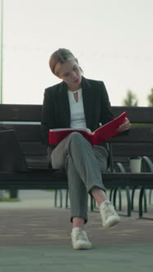 Woman reads in park sitting on bench