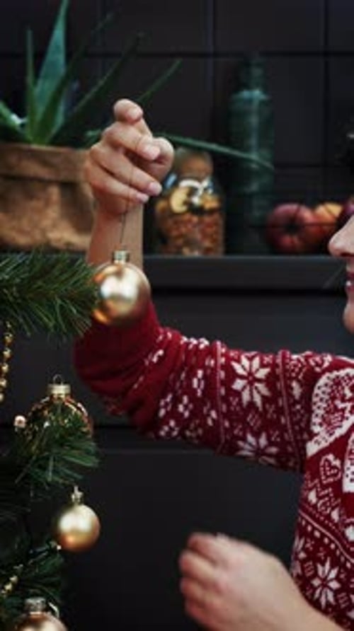 Close up of brunette woman decorating Christmas tree with balls. Vertical video