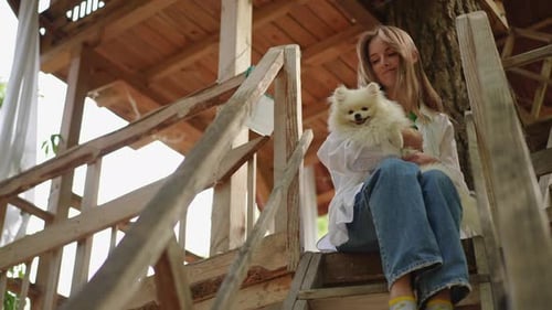 Woman with Dog on Wooden Treehouse Steps