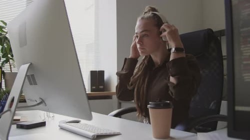 Une programmeuse met des écouteurs sans fil sur son lieu de travail