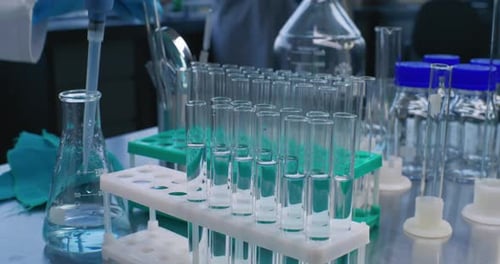 Close Up of Scientist Pouring Blue Into Test Tubes with Pipette