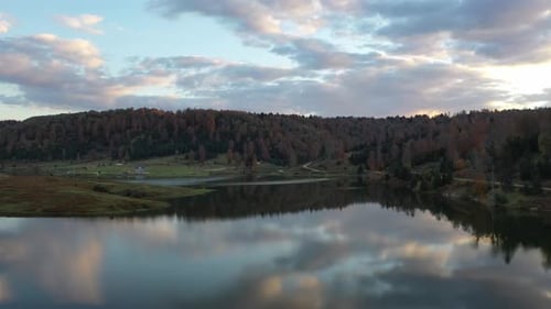 a lake in the forest and cloudy sky