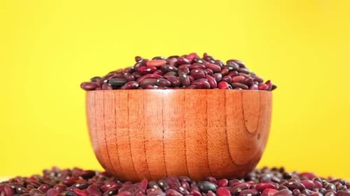 Kidney Beans Falling in Wooden Bowl on Yellow Background Slow Motion