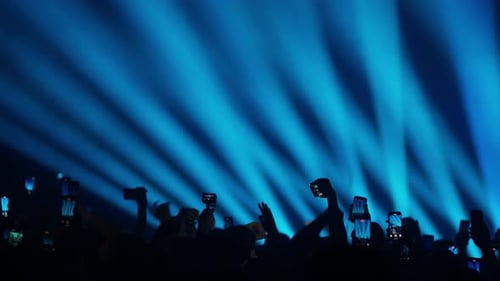 Energetic Crowd Silhouettes Applauding at Concert with Bright Lights