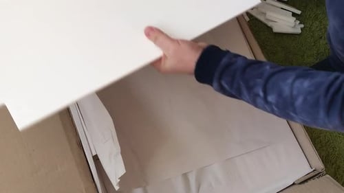 A Man Examines The Elements Of A Computer Desk Before Assembling. Takes The Elements Of The Product