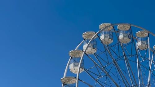 Vue à angle bas d'une grande roue tournant lentement sur un ciel bleu sous la lumière du soleil, 4K