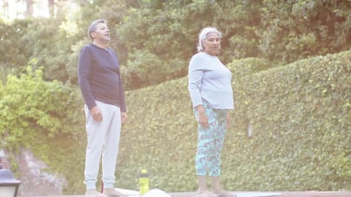 Focused diverse senior couple practicing yoga in garden