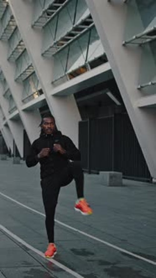 Sporty African American Athlete Training Alone Outdoors Warming Up His Legs Before Run Workout at