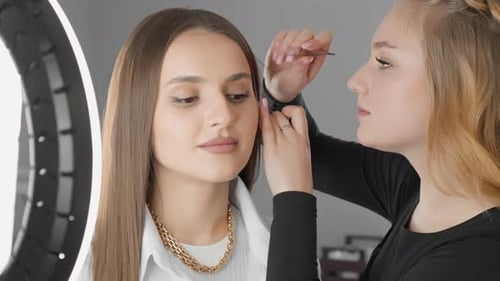 Woman Getting Eyebrows Shaped by Makeup Artist