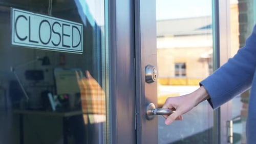 Woman attempts to open closed small business door during coronavirus pandemic