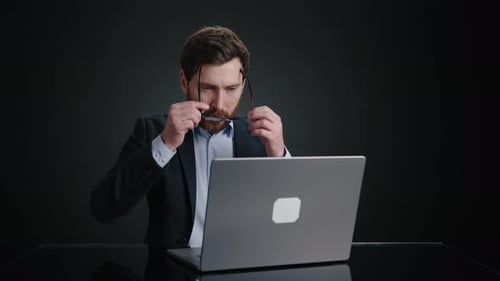 Focused Man Working on Laptop with Glasses