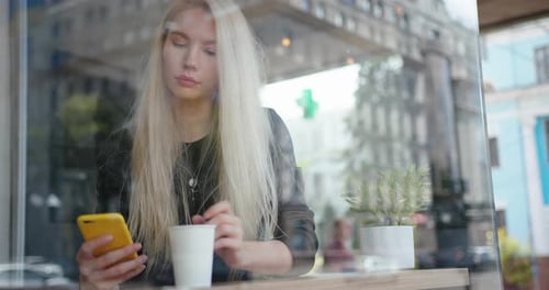 Mixed Race Woman in a Street Cafe Reading a Text Message From Her Phone