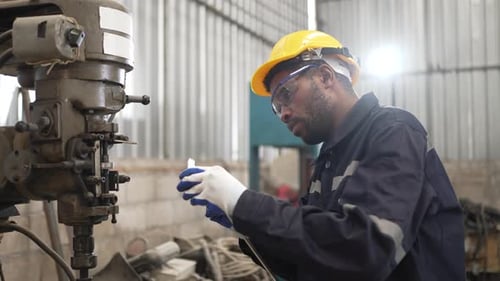 Blue collar workers at machine shop with welding robot arm.