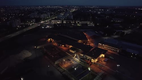 Aerial View of an Industrial Plant on the Banks of the River and the Panorama of the Night City with