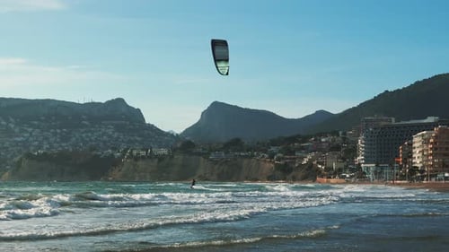 Man riding on kiteboard on huge sea waves.
