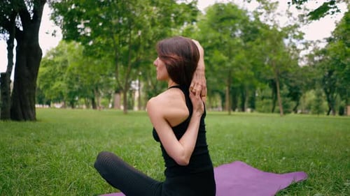 an experienced female instructor meditates in the park practices yoga does stretching and exercises