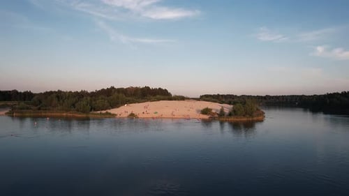 Shooting From a Quadcopter of a White Sand Beach on a Lake Where People Sunbathe and Swim on a