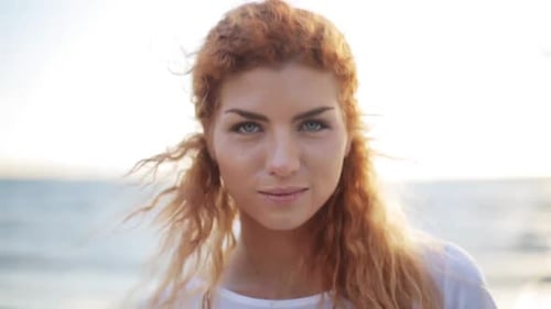 Smiling Woman with Red Curly Hair by the Ocean