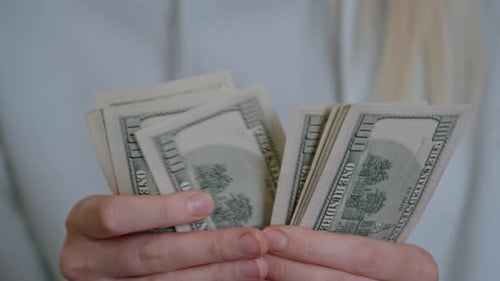 Close-up of female hands holding paper dollar banknotes.