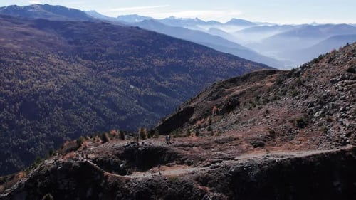 Opening aerial shot of a group of hikers on the mountain with trees full of autumn colors