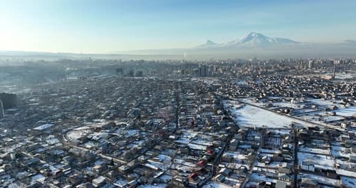 Aerial view of a village in Armenia in winter, with snow-covered roads and cars driving