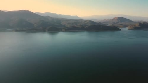 Aerial drone flying over a lake, water dam, with mountains at sunrise. Beautifull dreamy landscape