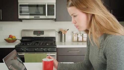 Woman Works on Laptop in Modern Kitchen