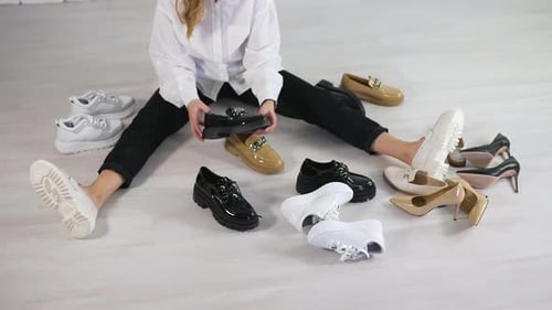 Woman Sits Surrounded by Fashionable Shoes