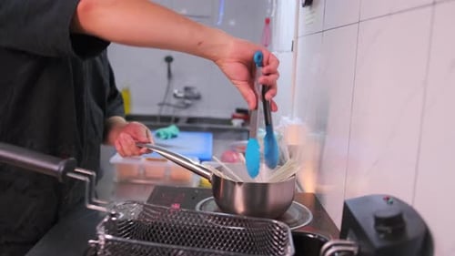 Chef Cooking Noodles in Kitchen with Tongs