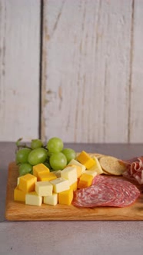 Hand place un verre de vin rosé à côté d'un plateau de charcuterie, de jambon serrano et de plats espagnols