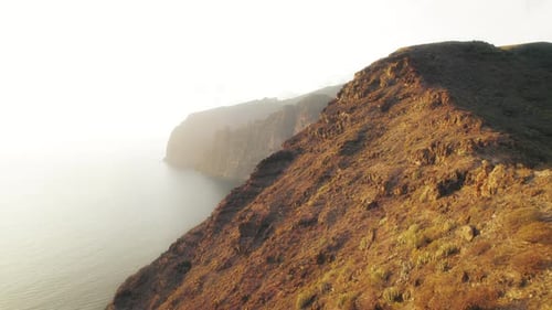 Rocky mountain ridge at sunset overlooking the ocean with Los Gigantes cliffs on the background.