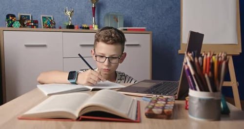 Boy Learning and Writing at Desk with Laptop